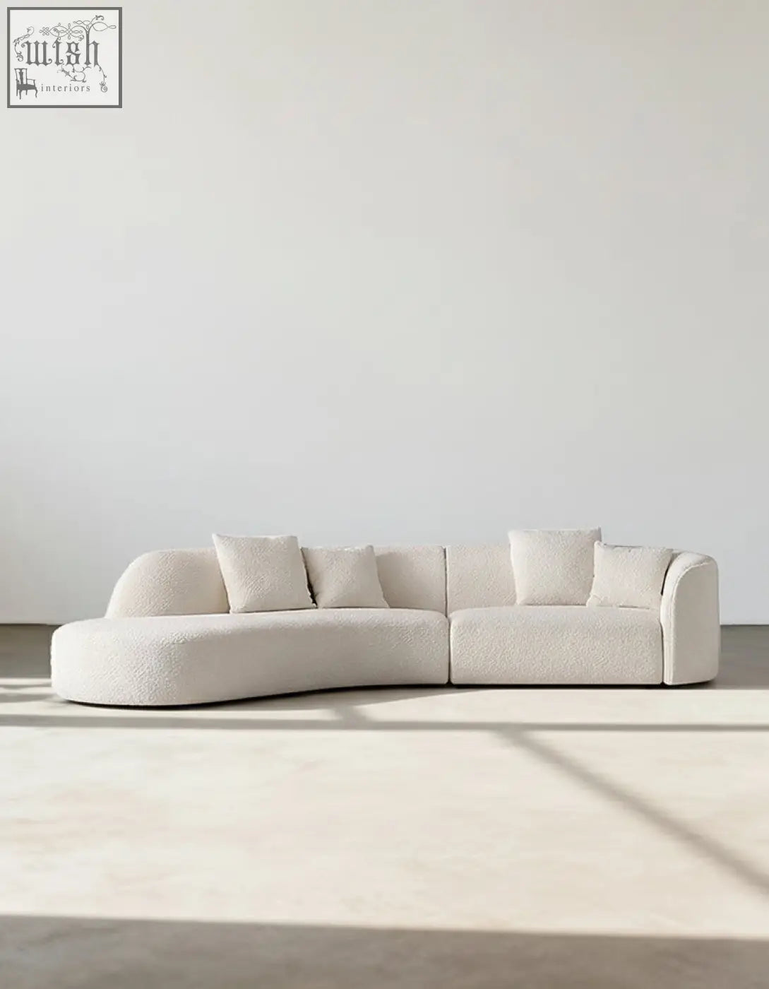 Cream-colored plush goldie gubi three seater sofa with curved boucle upholstery and matching square throw pillows