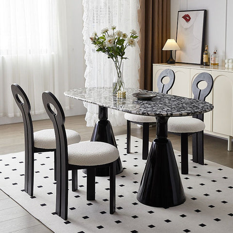 Black marble-top gordon dining table with sleek black conical legs and matching chairs with white upholstered seats