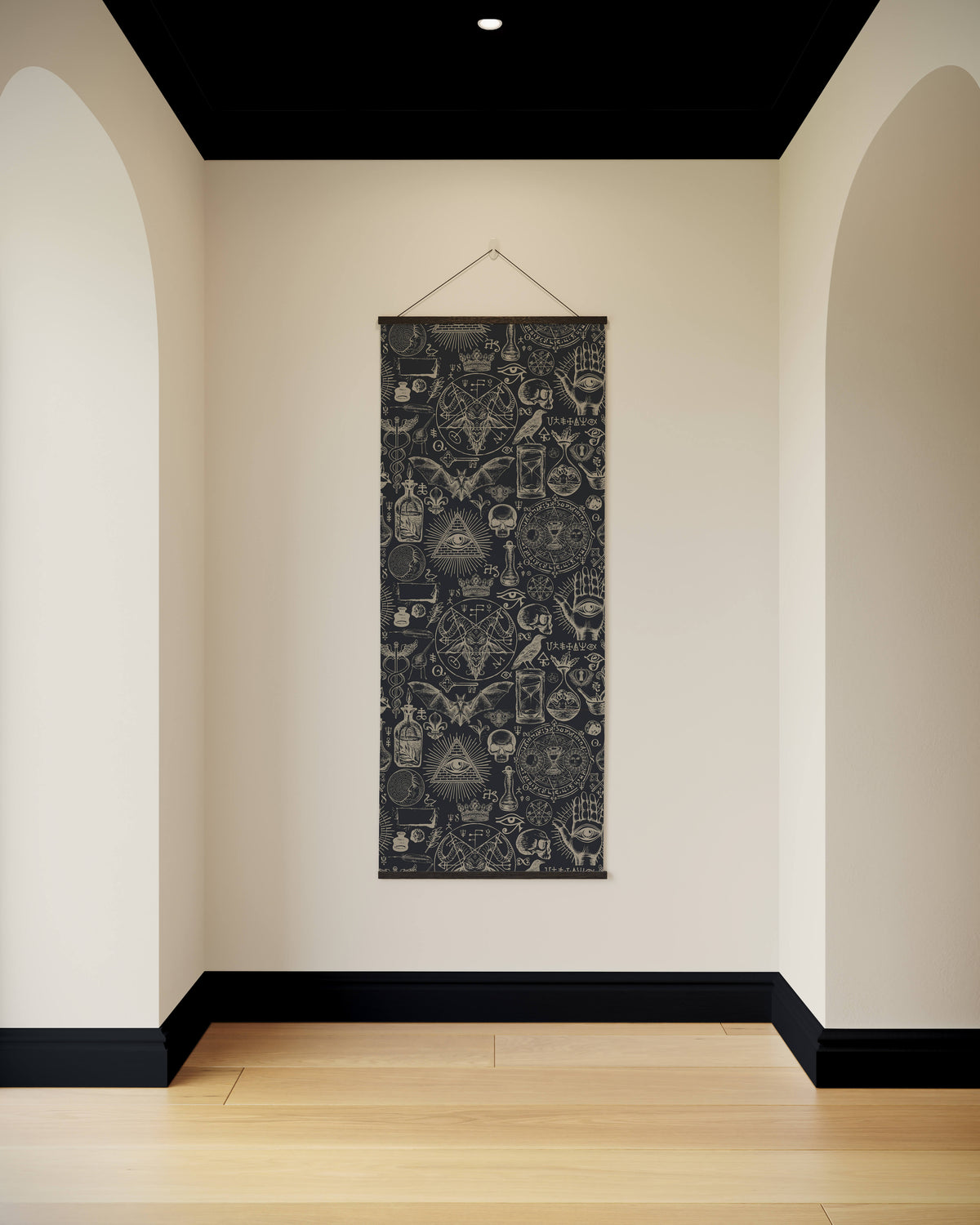 A black gothic occult tapestry with white intricate occult symbols and skulls hanging on a cream wall