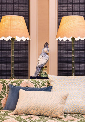 A decorative ceramic parrot with speckled gray and white body on a green base complements the gp baker cushion cover