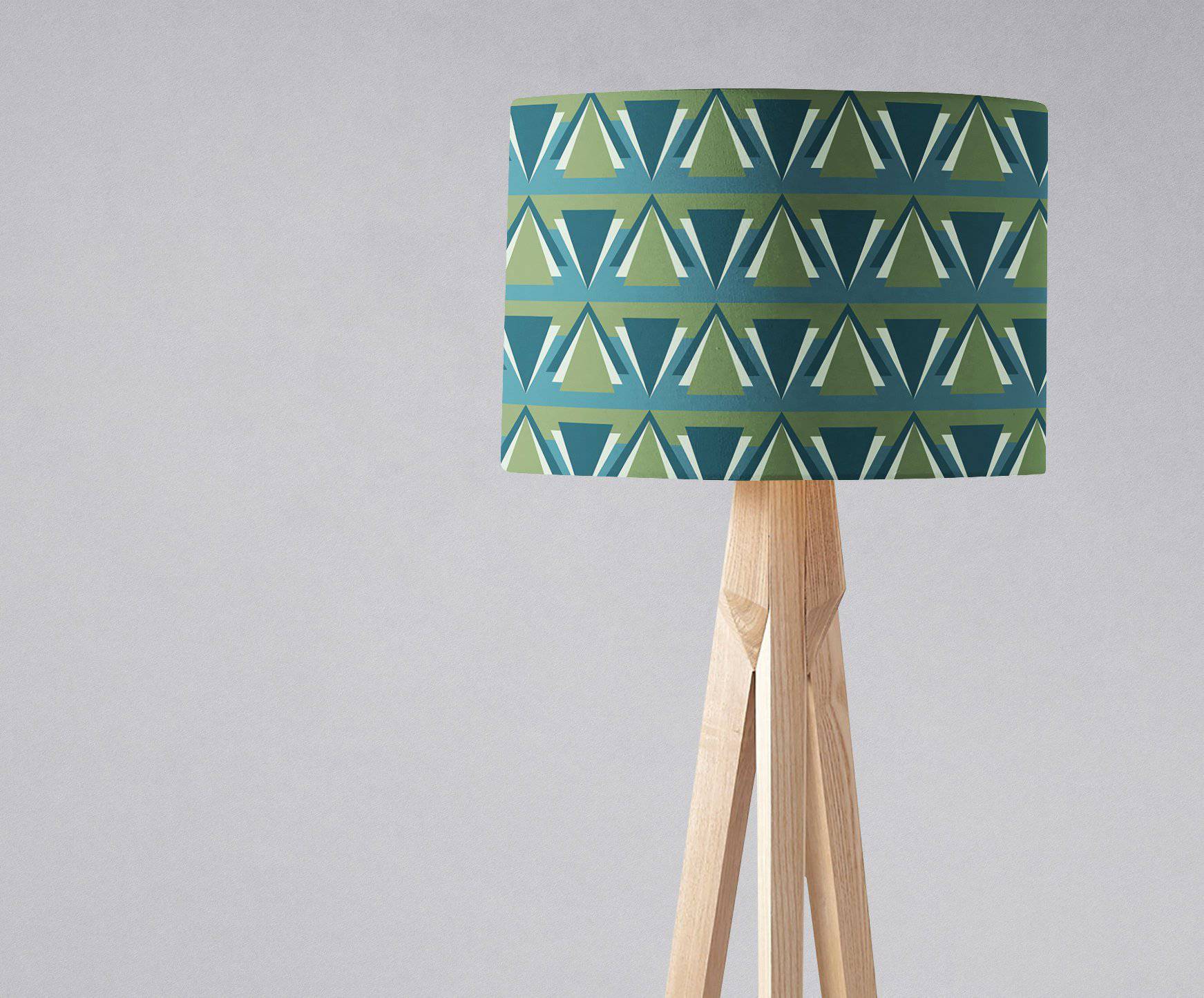 Cylindrical blue art deco lampshade with teal and olive triangles on a wooden tripod table lamp base