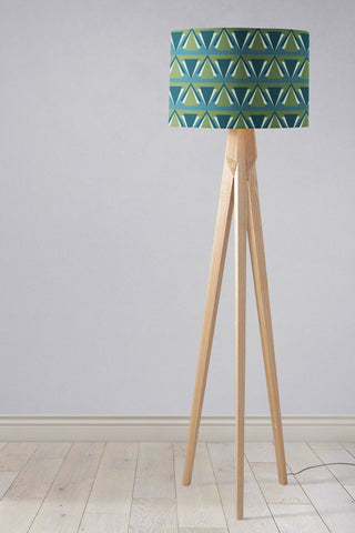 A modern tripod floor lamp with a blue art deco lampshade featuring teal and green geometric triangles on wooden legs