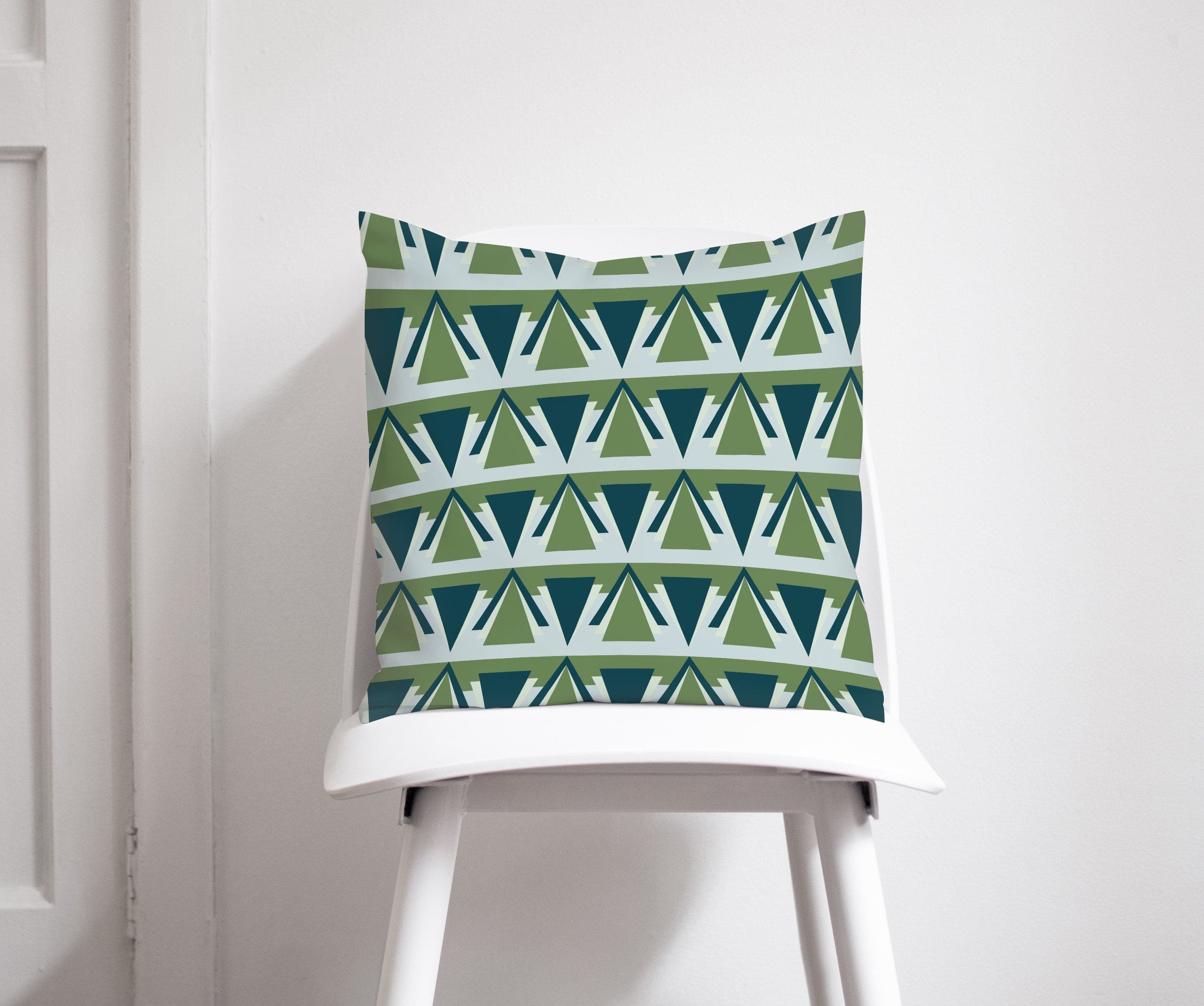 A green and grey art deco throw pillow with eye catching geometric triangles on a white chair
