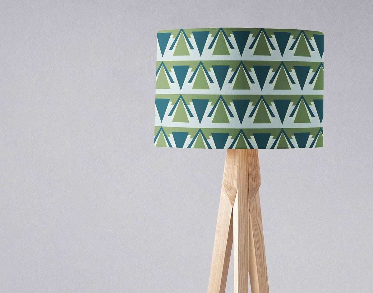 Green and grey art deco lampshade with geometric green and teal triangles on a wooden tripod table lamp base