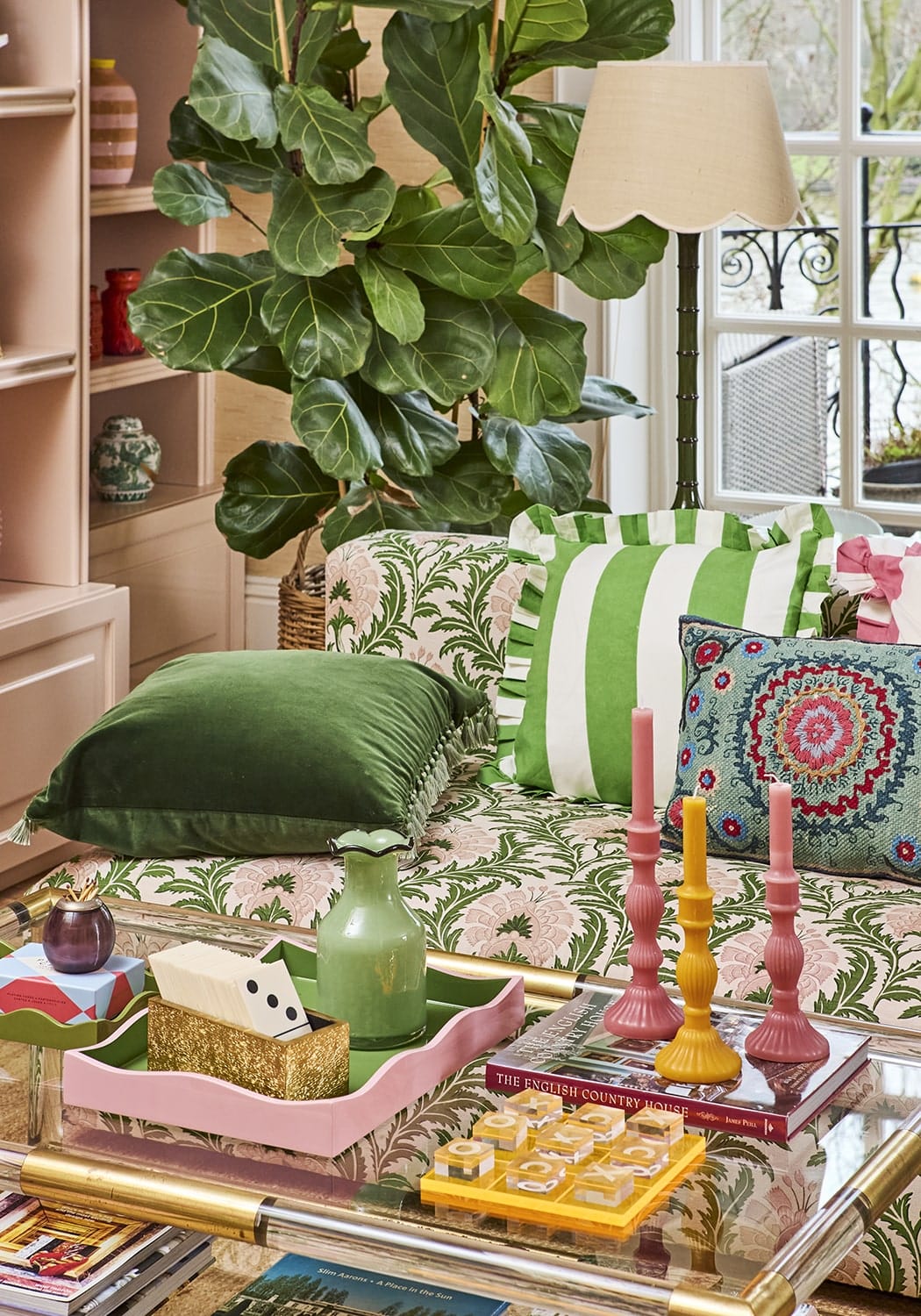Pink tray with scalloped edges holding green ceramic vase and decorative items next to green cabana stripe ruffled cushion cover