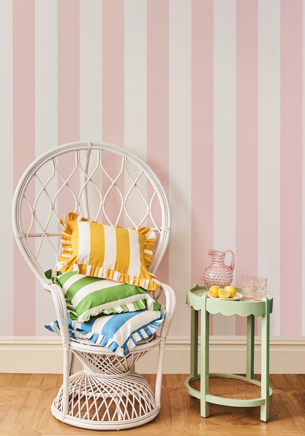 White wicker peacock chair with colorful green cabana stripe ruffled cushion cover and striped pillows