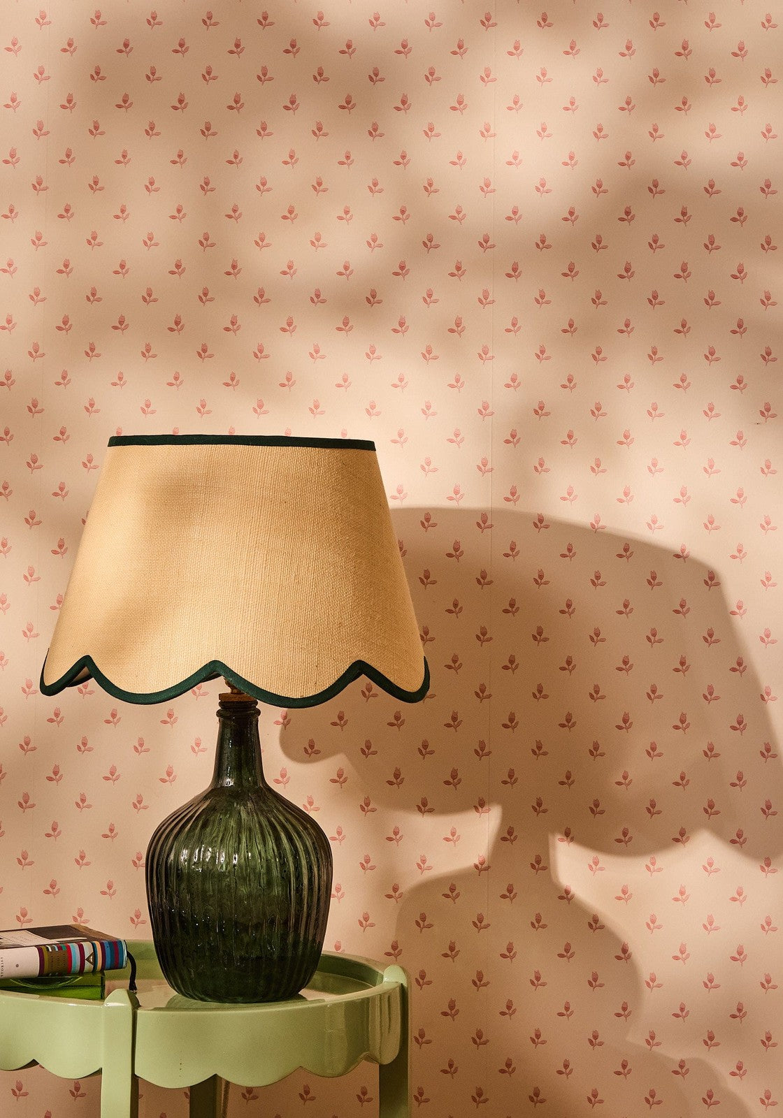 A dark green ribbed glass lamp with a beige scalloped jute lampshade edged in black perfect for cozy lighting