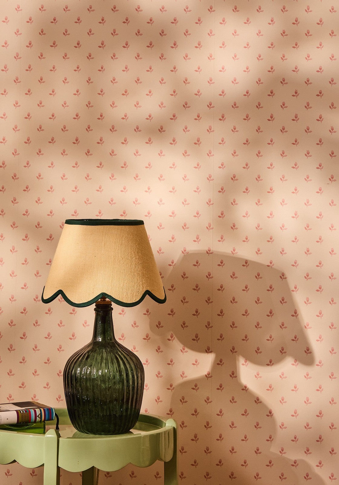 A dark green ribbed glass table lamp with a beige green petal jute scallop lampshade edged in black