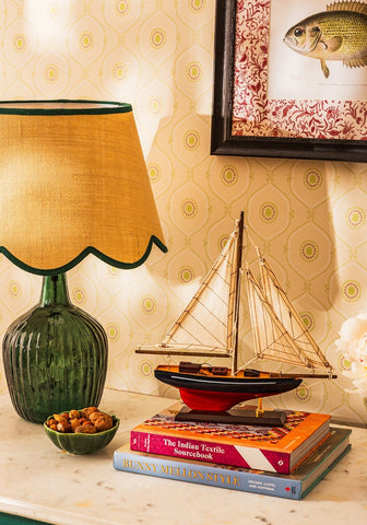 A vintage green glass lamp with a ribbed base and a mustard yellow linen green edged green petal jute scallop lampshade
