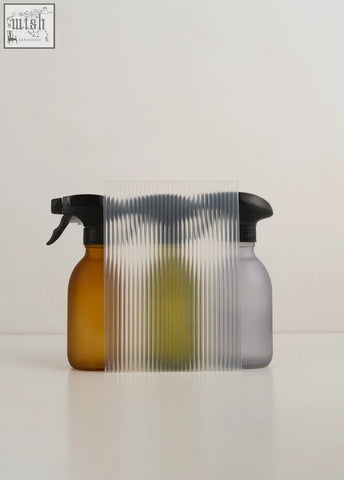 Two spray bottles one amber one gray with black nozzles green glass spray glass spray bottle combo