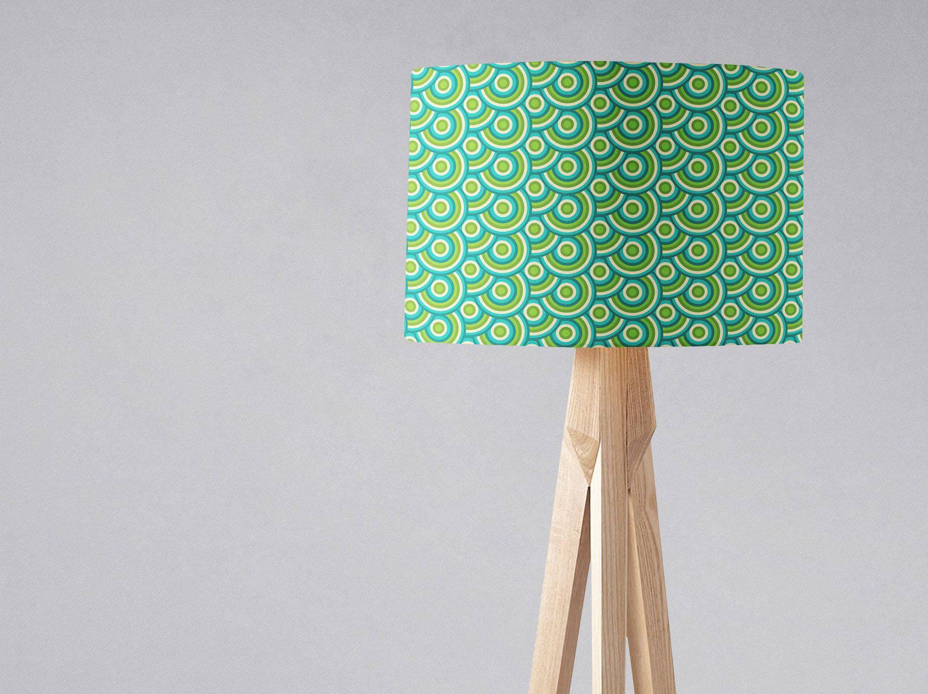 Green 70s retro circles design lamp shade in teal and lime green on a light wood tripod base for table lamp use