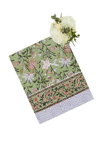 Green with envy floral print tablecloth with pink and white floral pattern and geometric border on a rectangular green runner