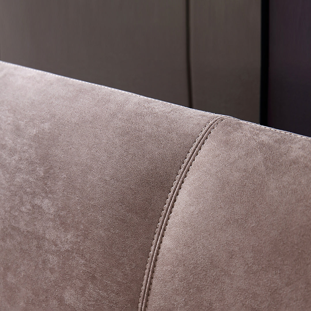 Armrest of a taupe suede greta king size and super king size bed with neat stitching along its curved edge