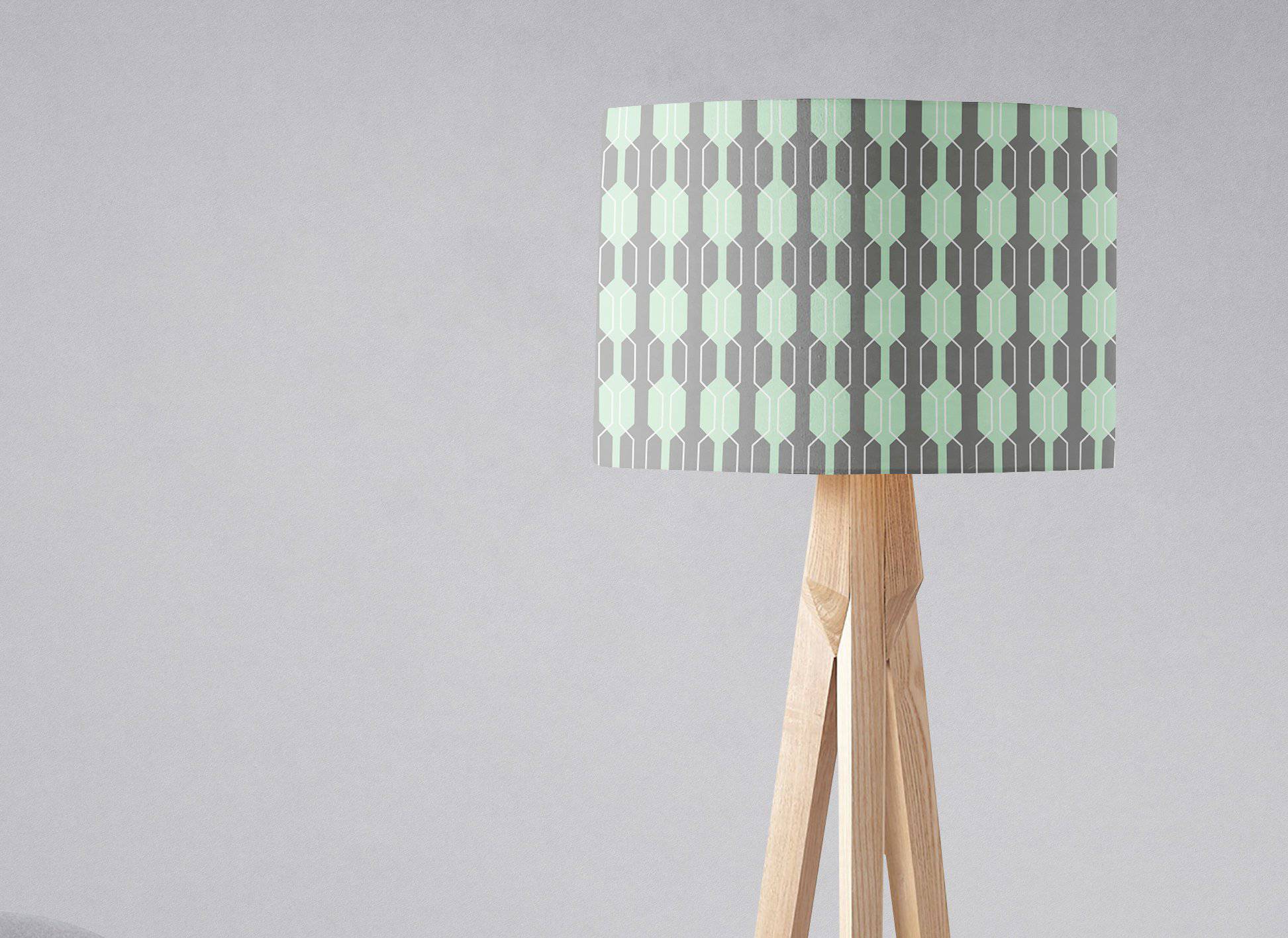 Grey lampshade with a mint green geometric design on a light wood tripod table lamp base