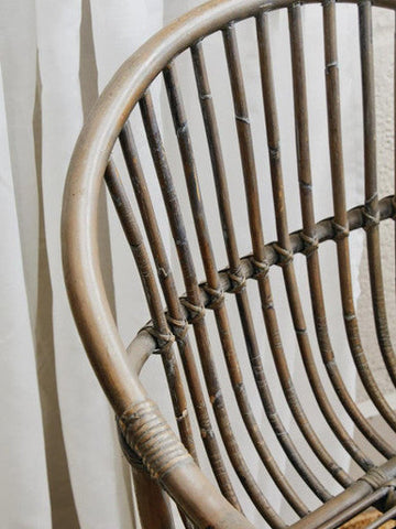 Curved grey wash natural rattan chair with woven detailing and a weathered finish perfect for indoor seating