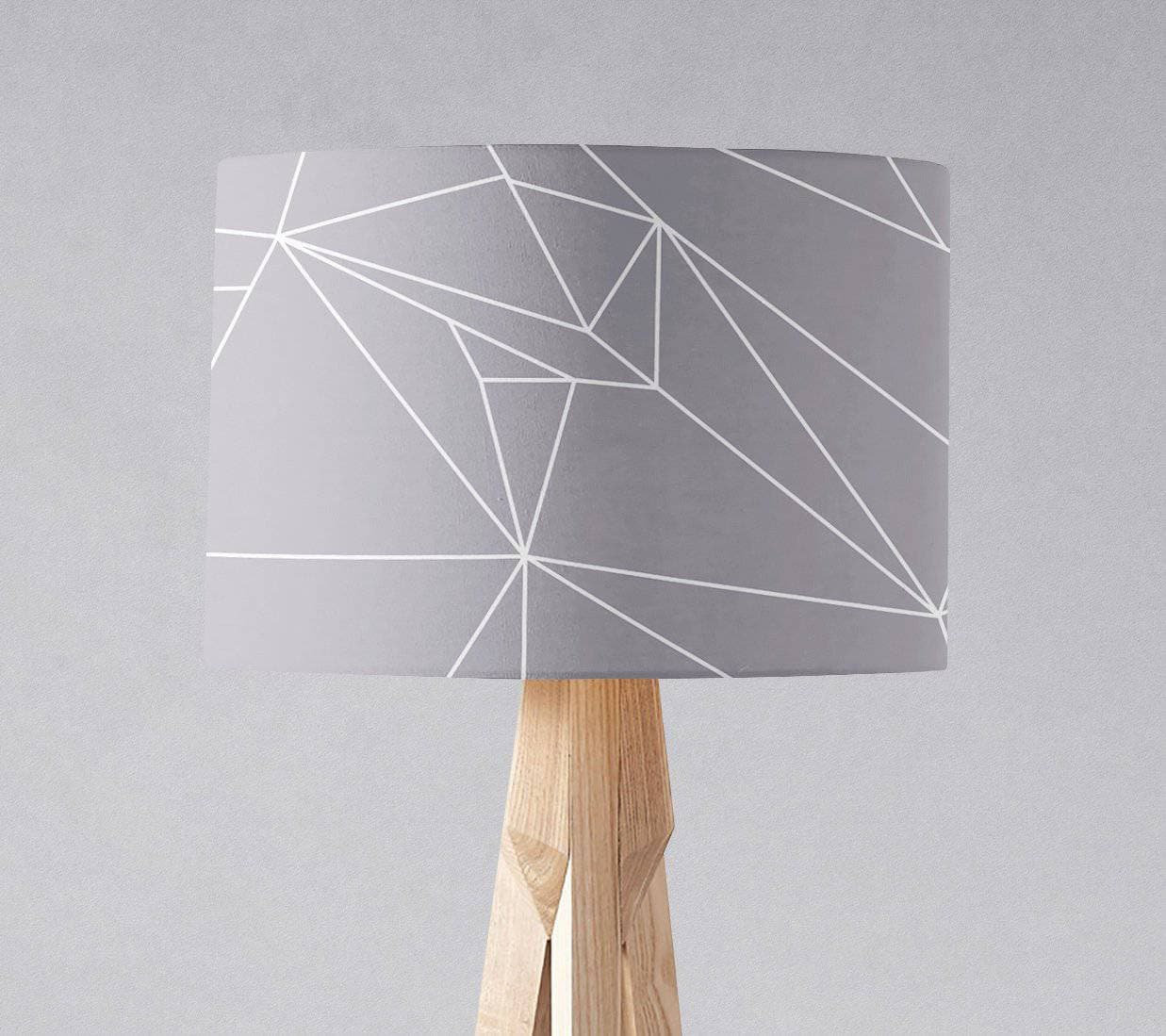 Gray table lamp shade with white line geometric design on light wood tripod base with inch diameter size