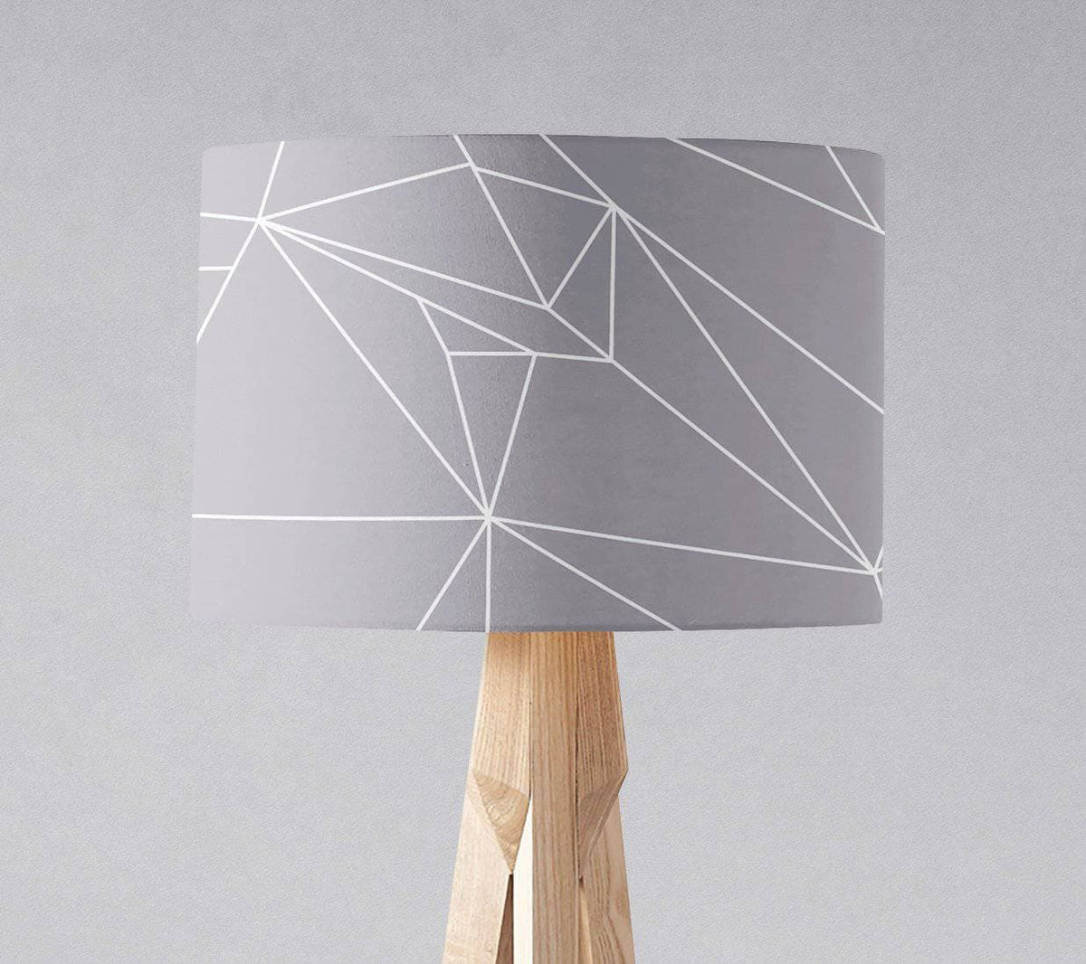 Gray table lamp shade with white line geometric design on light wood tripod base with inch diameter size