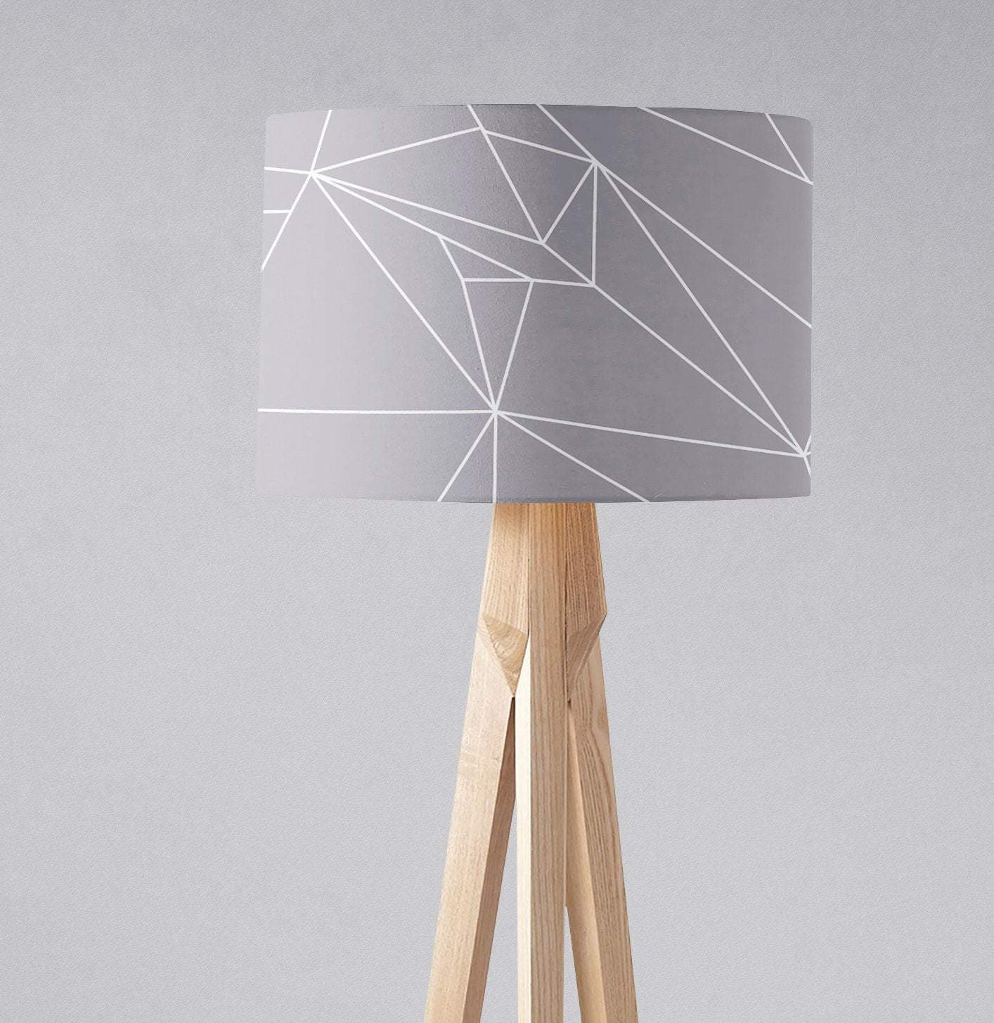 Gray table lamp shade with white geometric lines on light wood tripod base 12 inch diameter