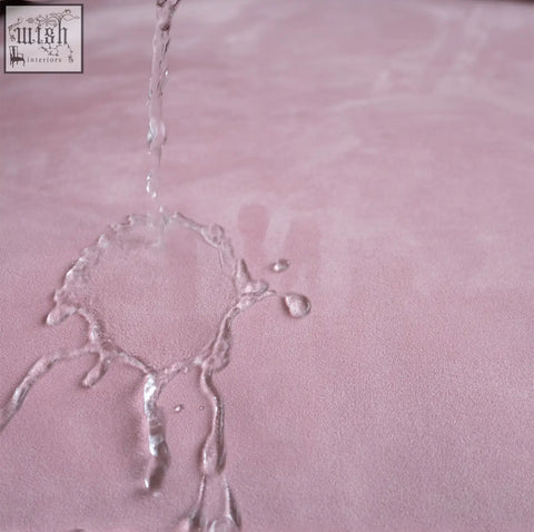 Soft pink suede surface of the grimm three seater sofa with water droplets on its textured matte finish
