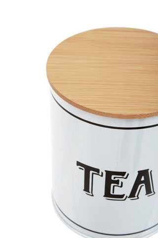 White metal tea canister grocer with a cylindrical design, light wood lid, and black tea lettering