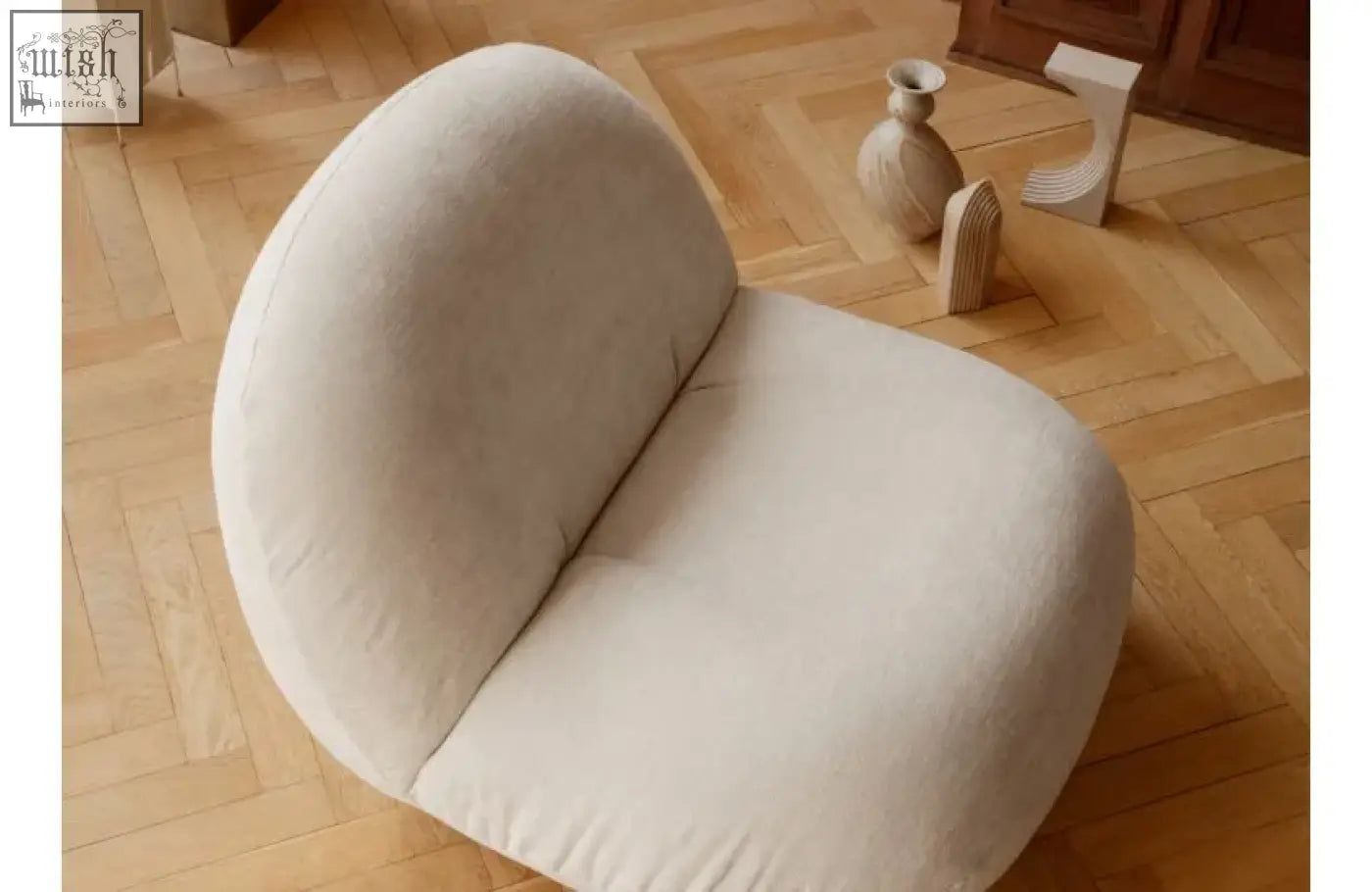 Cream-colored plush upholstered gubi pacha accent chair with boucle fabric and minimalist gold base design