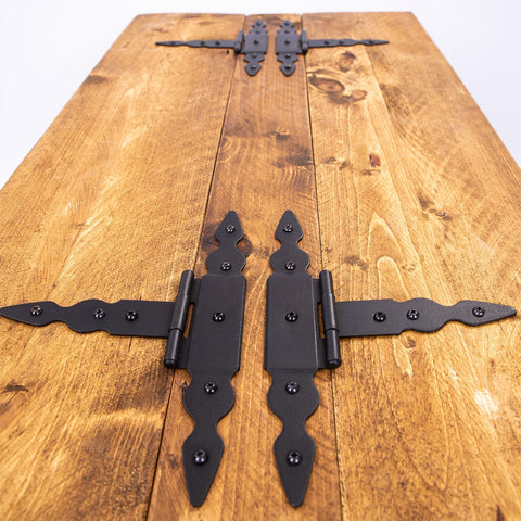 Black wrought iron decorative hinge set with ornate pointed ends on a wooden storage coffee table chest