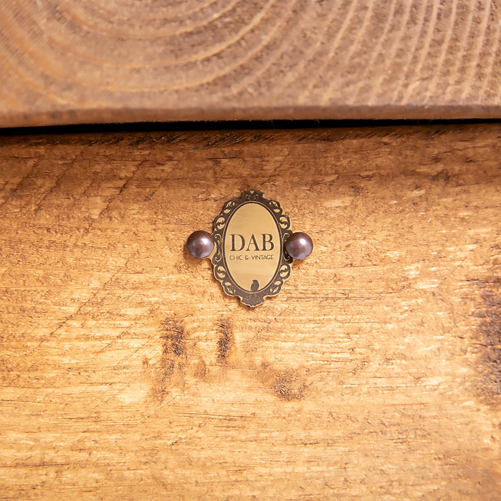 Antique brass oval plaque with ornate border and dark purple pearls on wooden blanket box hairpin storage chest