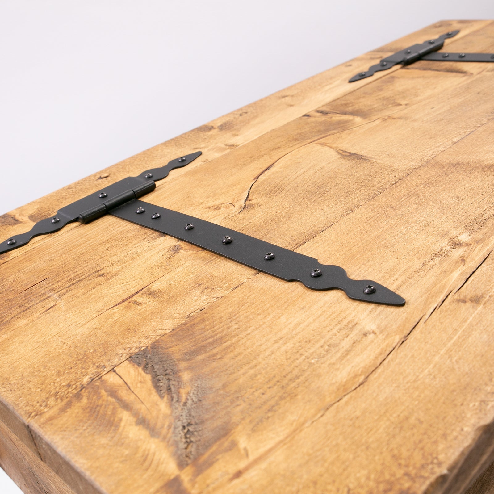 Black wrought iron strap hinge with scroll ends on a rustic wooden blanket box for hairpin storage chest trunk