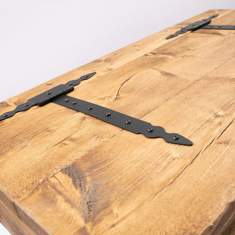 Black wrought iron strap hinge with scroll ends on a rustic wooden blanket box for hairpin storage chest trunk