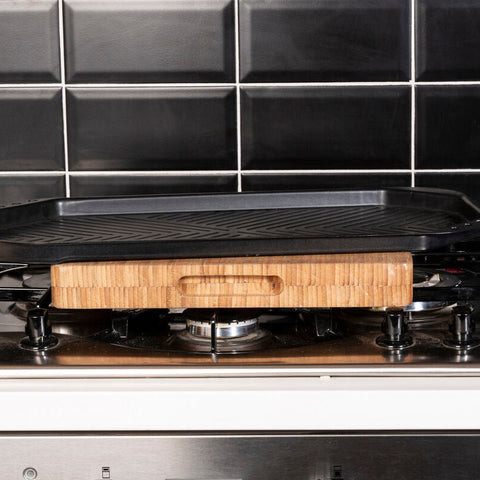 Black halston non stick large grill pan with wooden handle resting on gas stove for easy stick large grilling