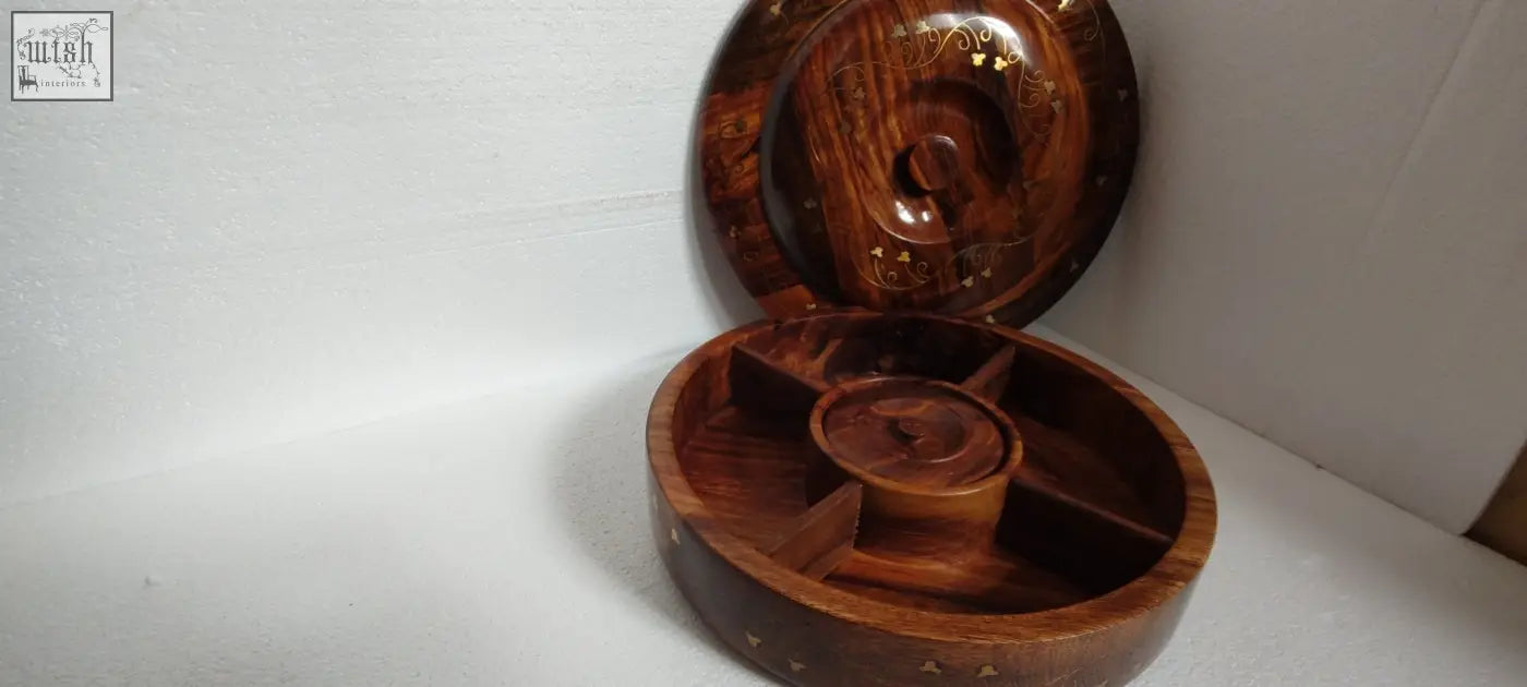 A hand crafted sasswood round fruit serving tray with glossy finish and intricate gold inlaid patterns on lid and compartments