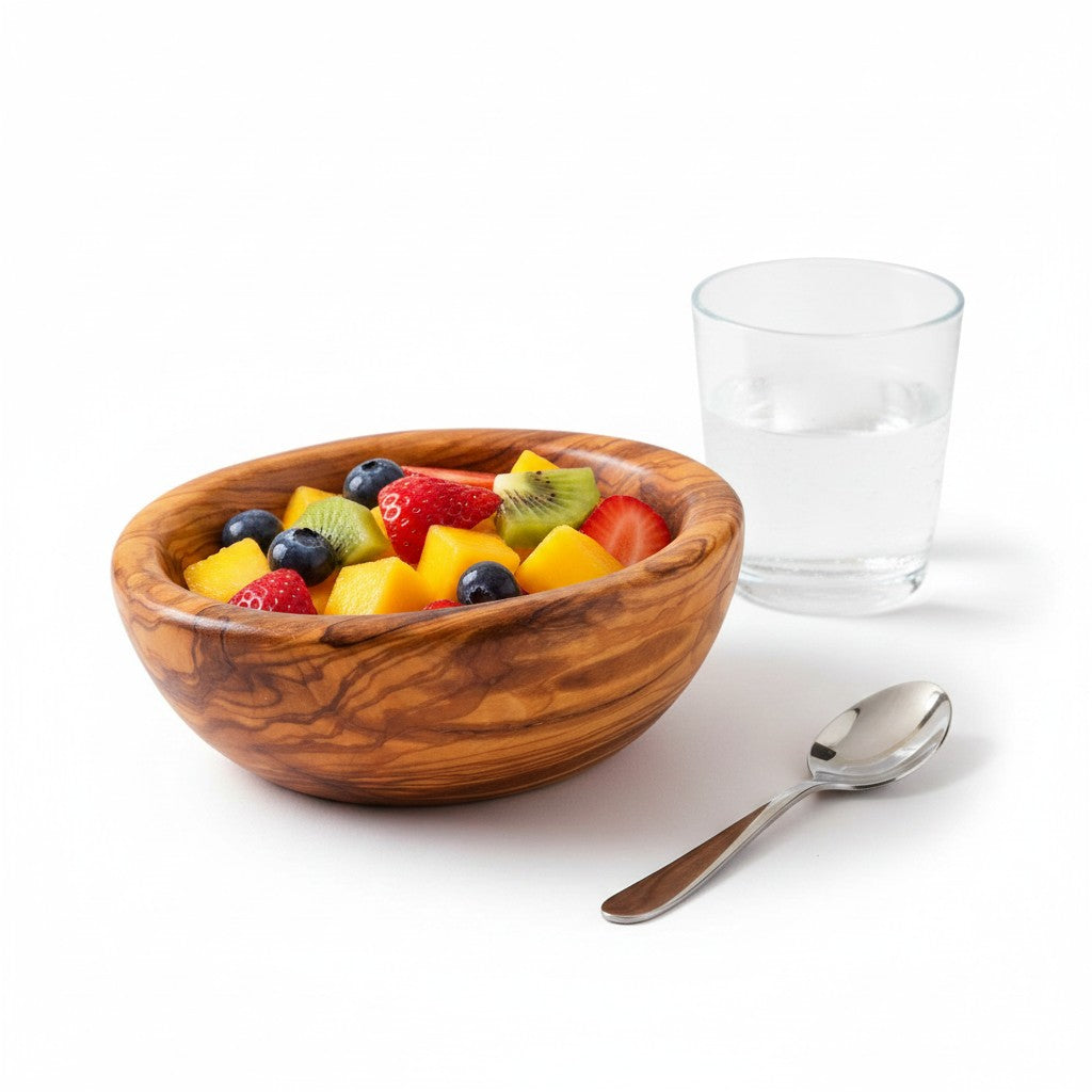 A handmade olive wood bowl with a silky polished interior filled with colorful fresh fruit showing natural grain