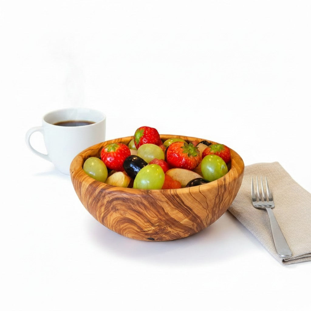 Handmade olive wood bowl with silky polished interior filled with fresh strawberries green and black olives