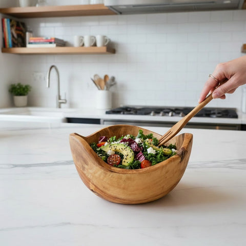 A rustic light brown olive wood salad bowl with unique natural bark edge holding fresh greens and veggies
