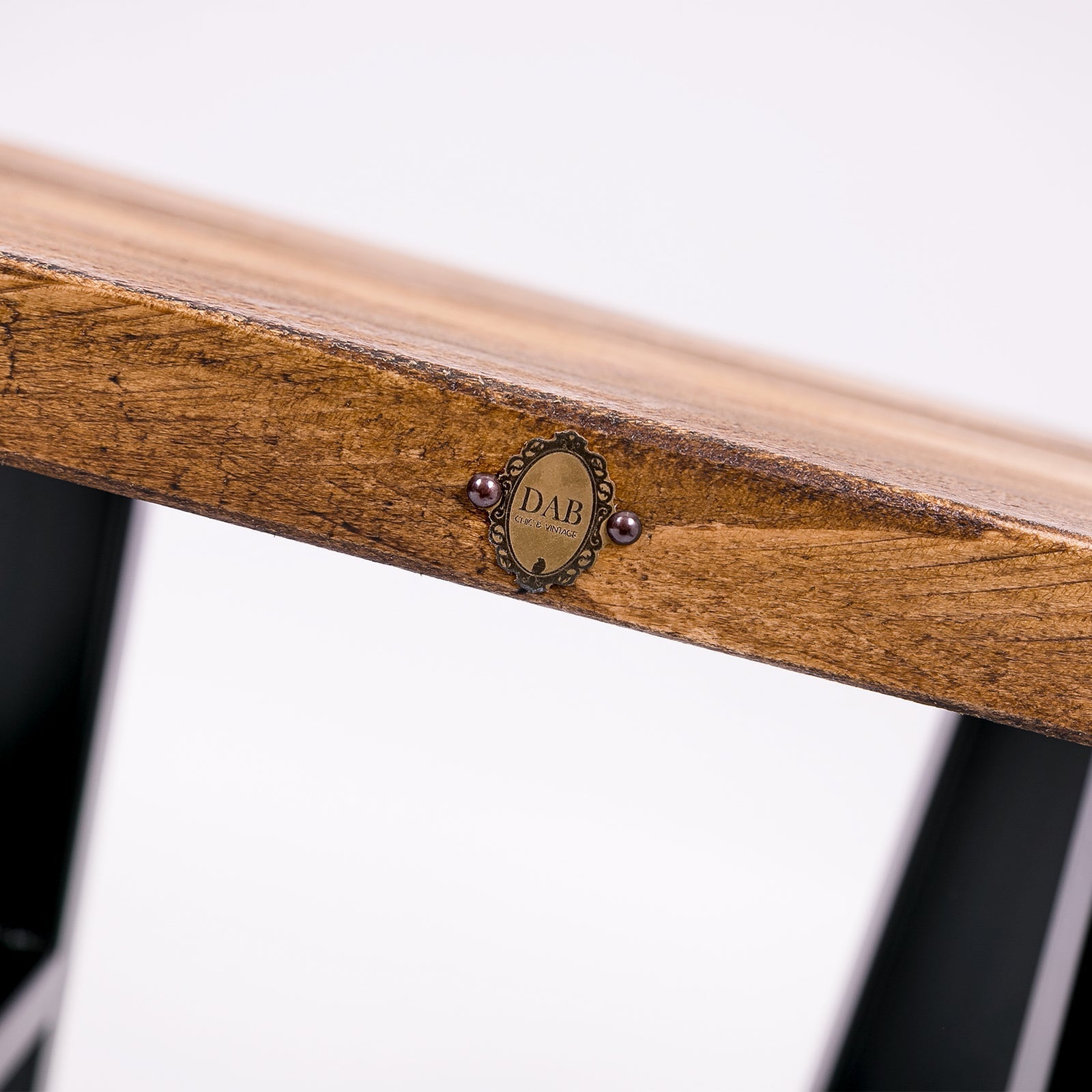 A handmade solid wooden stool with steel legs featuring a rustic wooden table top and ornate dab brass plaque