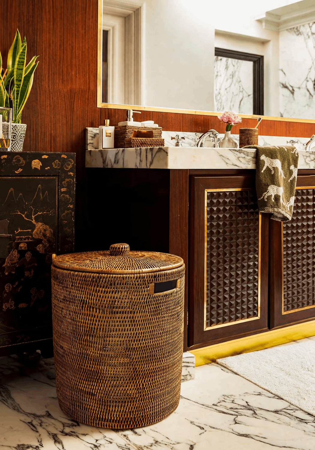 Handwoven luxe washing hamper made of brown rattan with a matching lid and small black handle for laundry storage