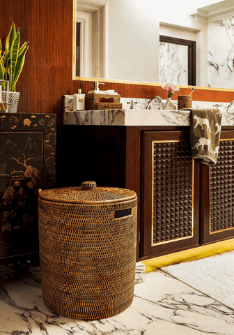 Handwoven luxe washing hamper made of brown rattan with a matching lid and small black handle for laundry storage