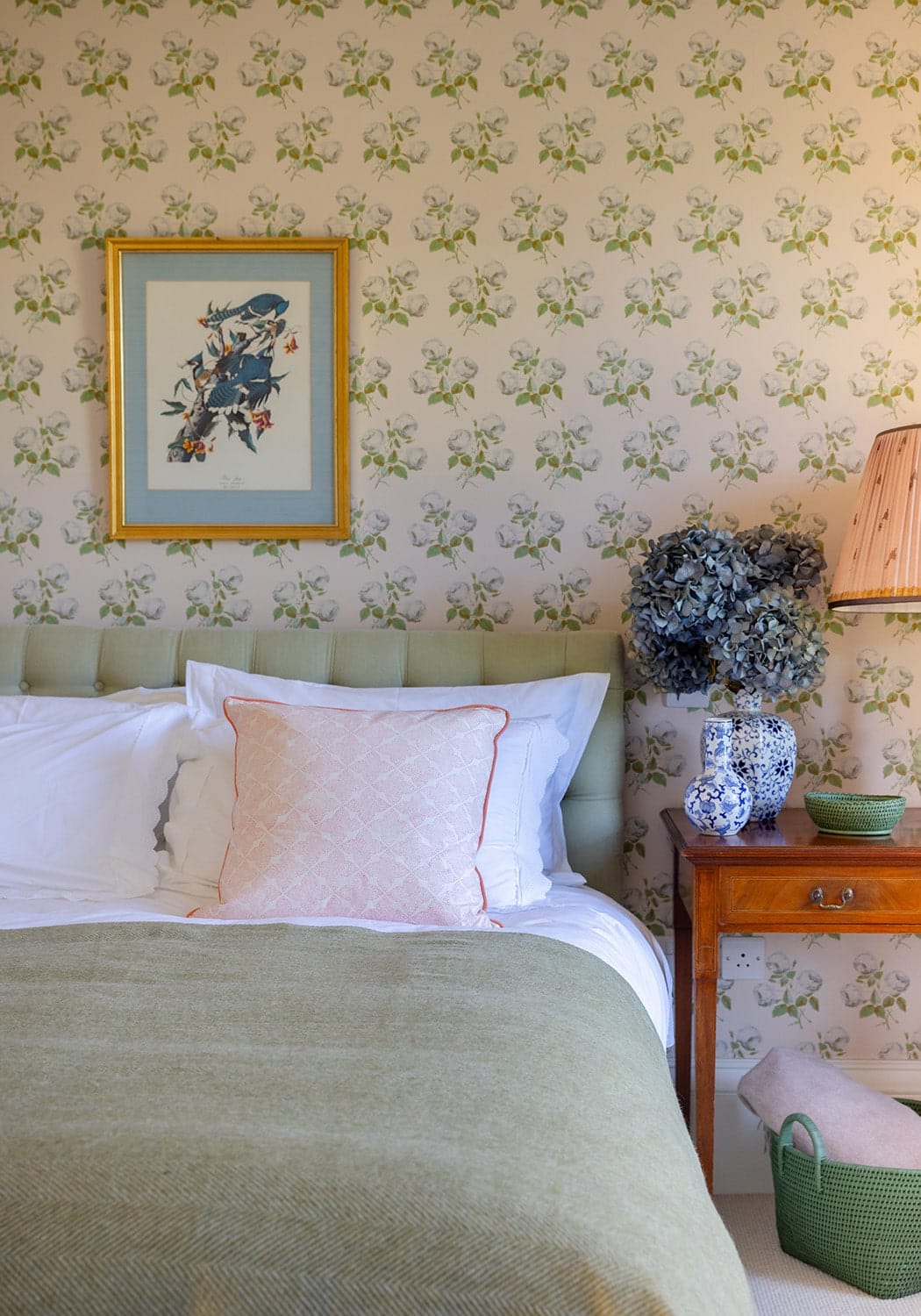 Handy handwoven green rattan basket holding a delicate blue and white porcelain vase with dried hydrangeas