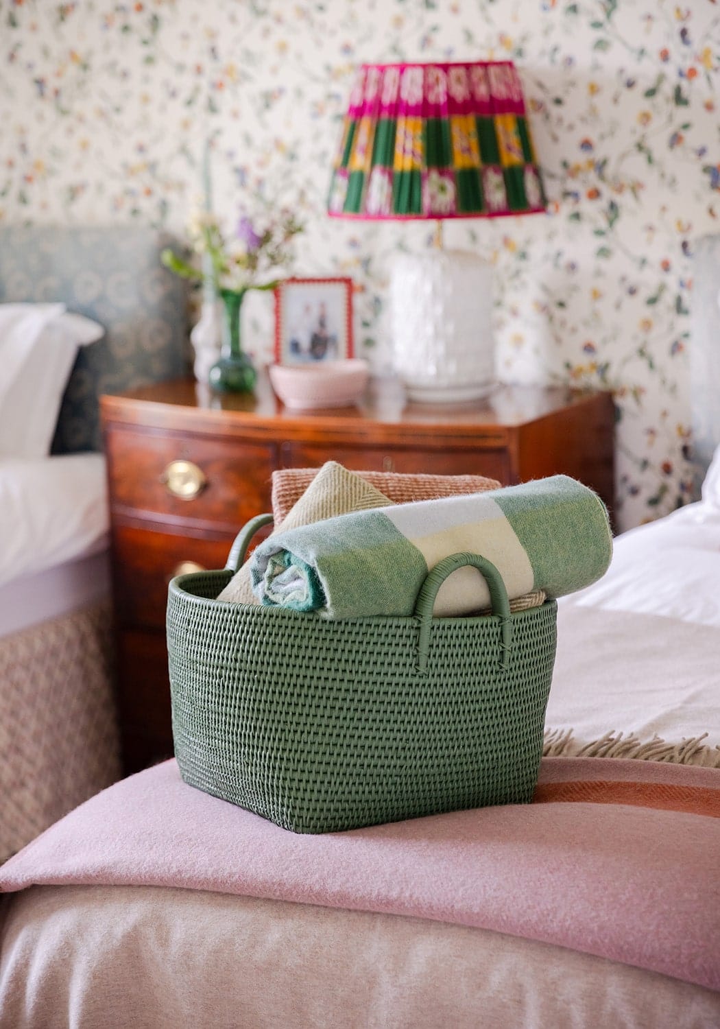 Handy handwoven rattan basket in green with a rolled green and white striped blanket inside