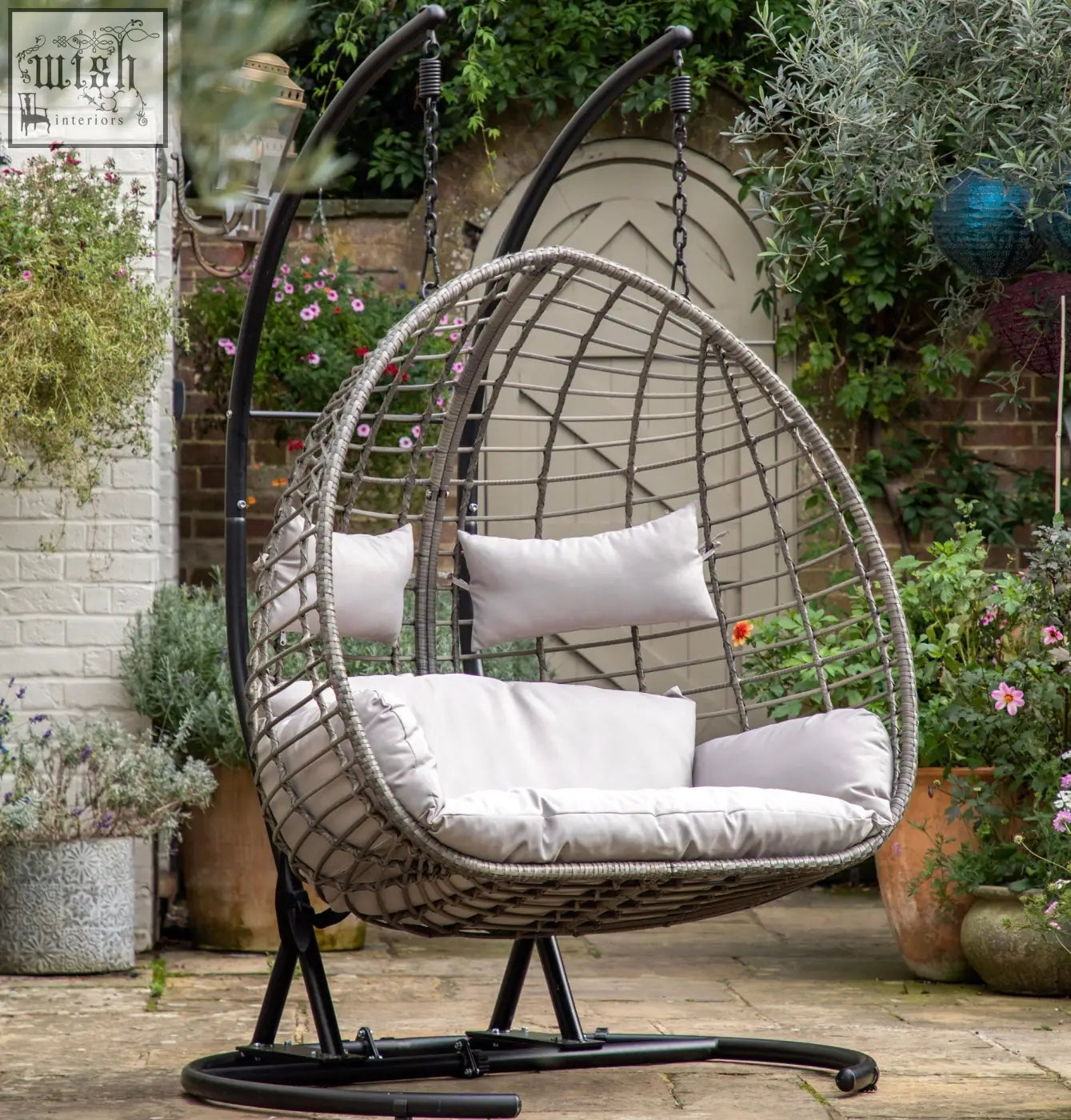 Gray woven hanging swing egg sofa with white cushions and power coated steel frame for indoor outdoor use