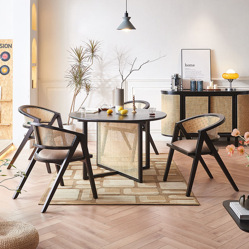 Black round dining table with woven rattan cane base and panels in a sleek modern design perfect for dining rooms