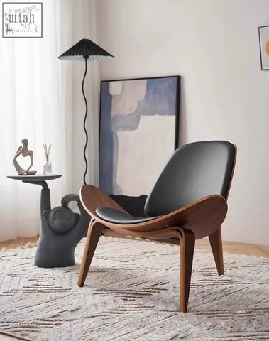 Modern mid-century ch07 shell chair with sleek black leather seat and curved walnut wood legs perfect for lounging