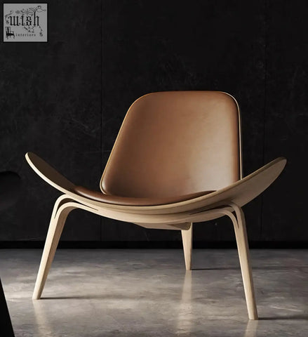 A hans wegner ch07 shell chair with a light oak frame and tan leather upholstery perfect for minimalist spaces
