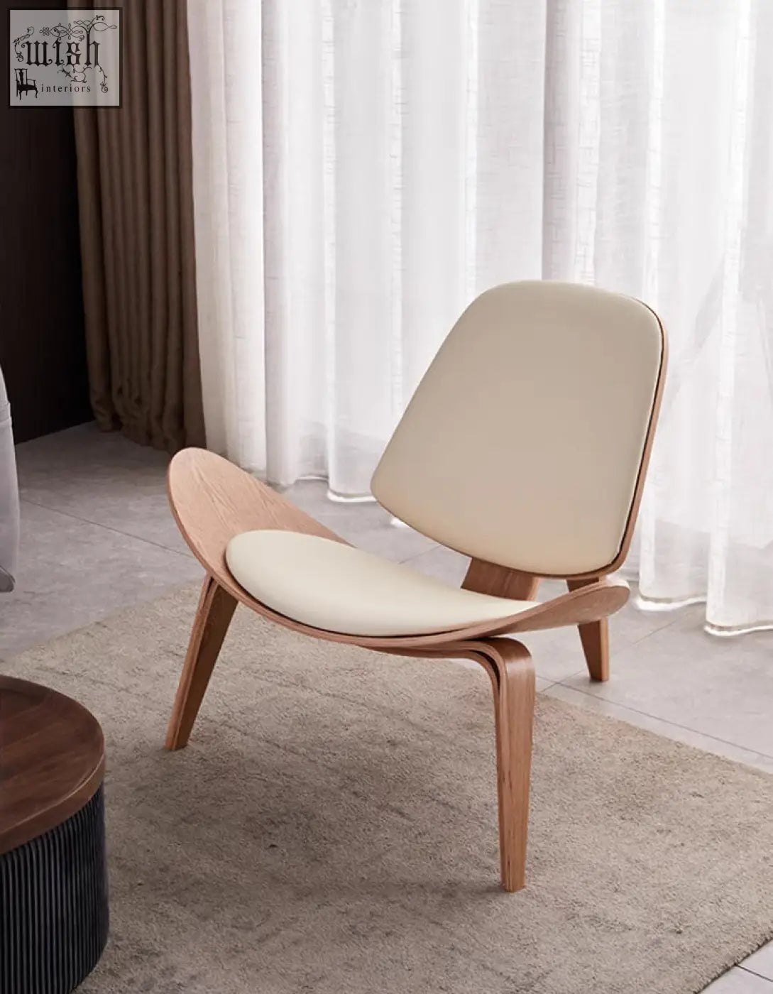 Cream-colored hans wegner ch07 shell chair with curved light oak frame and upholstered lounge seat