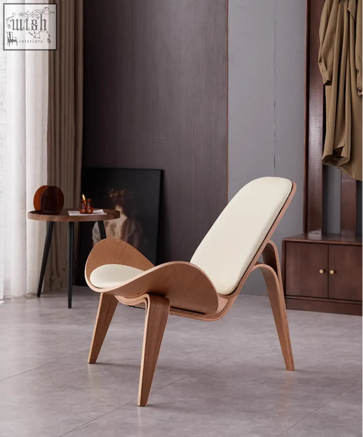 Modern hans wegner armchair with white ash frame and cream cushions in sleek curved shell chair design