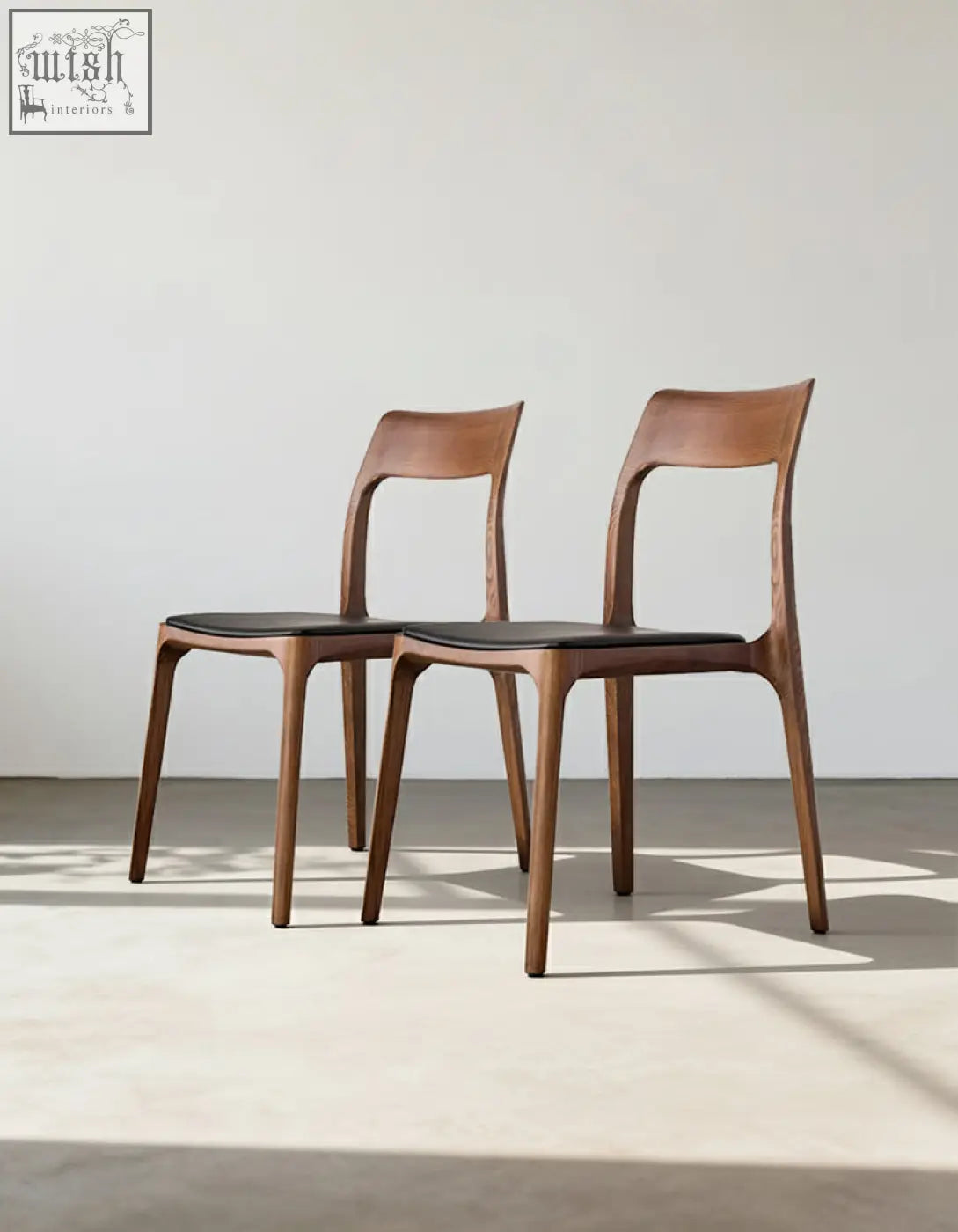 Two hans wegner ch3 dining chairs in dark oak with sleek curved wooden frames and black leather seats