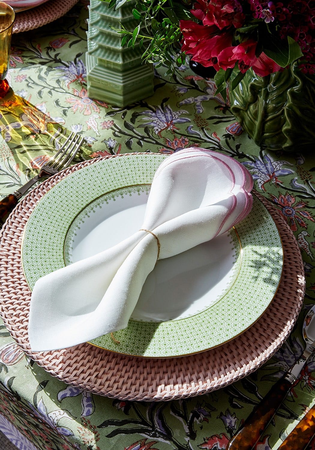 White linen napkin with pink border tied with gold cord on harbour island round rattan charger placemat pink set of 4