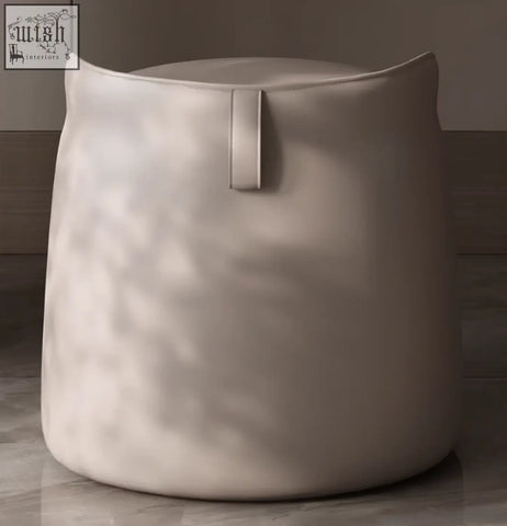 Beige upholstered ottoman with rounded shape and vertical strap detail paired with sintered stone dressing table shipping cost info