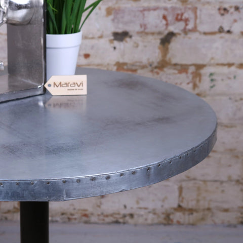 Circular metal hatra industrial style side table with matte silver finish and riveted edge