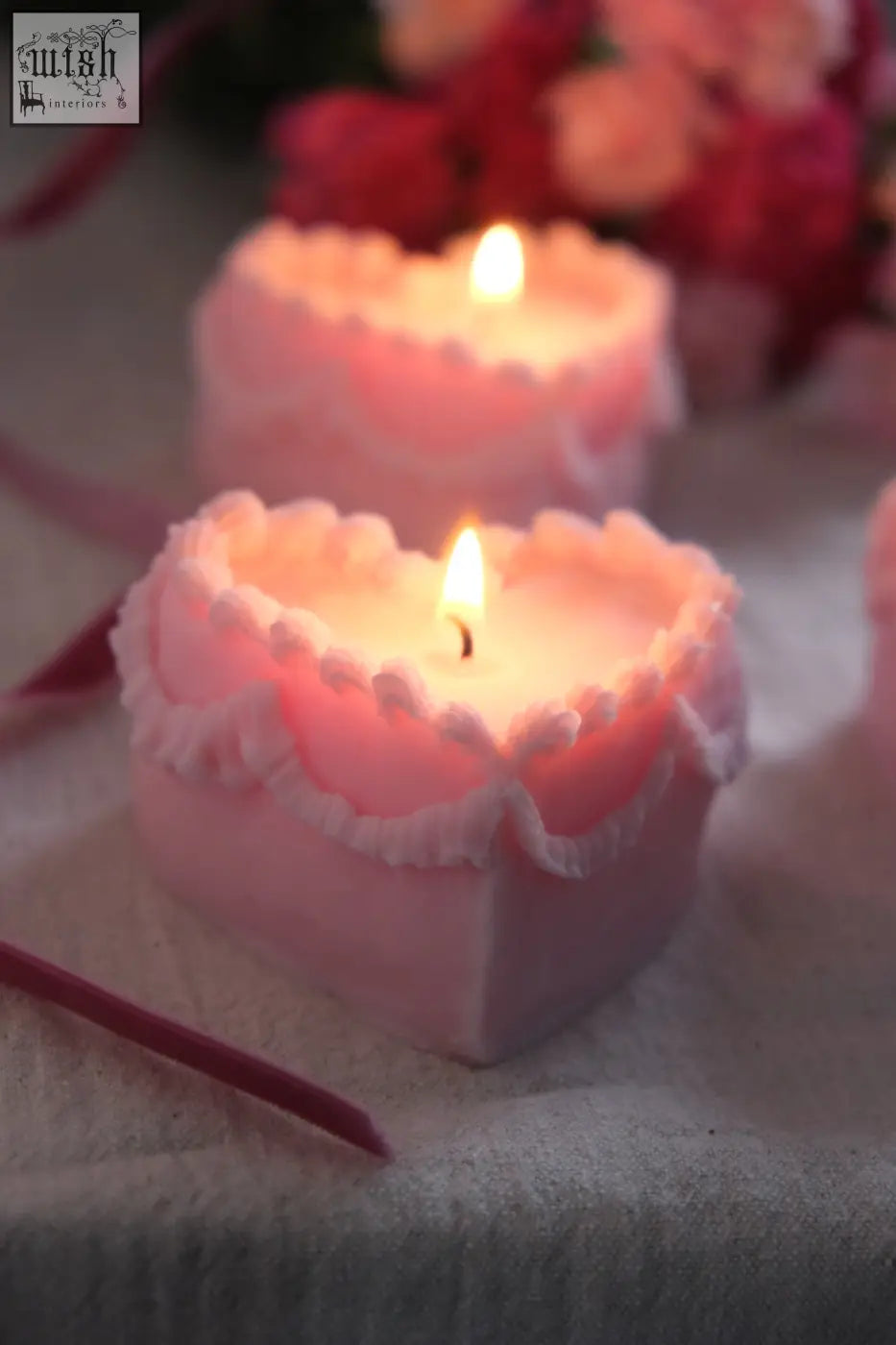 Pink heart cake candle with white ruffled edges and a lit wick perfect as a unique cake candle